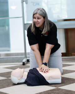 A woman demonstrates CPR on a dummy