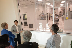 A tour group talks outside of a cleanroom.