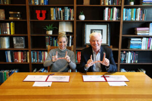 Two people make U shapes with their hands after signing documents. 